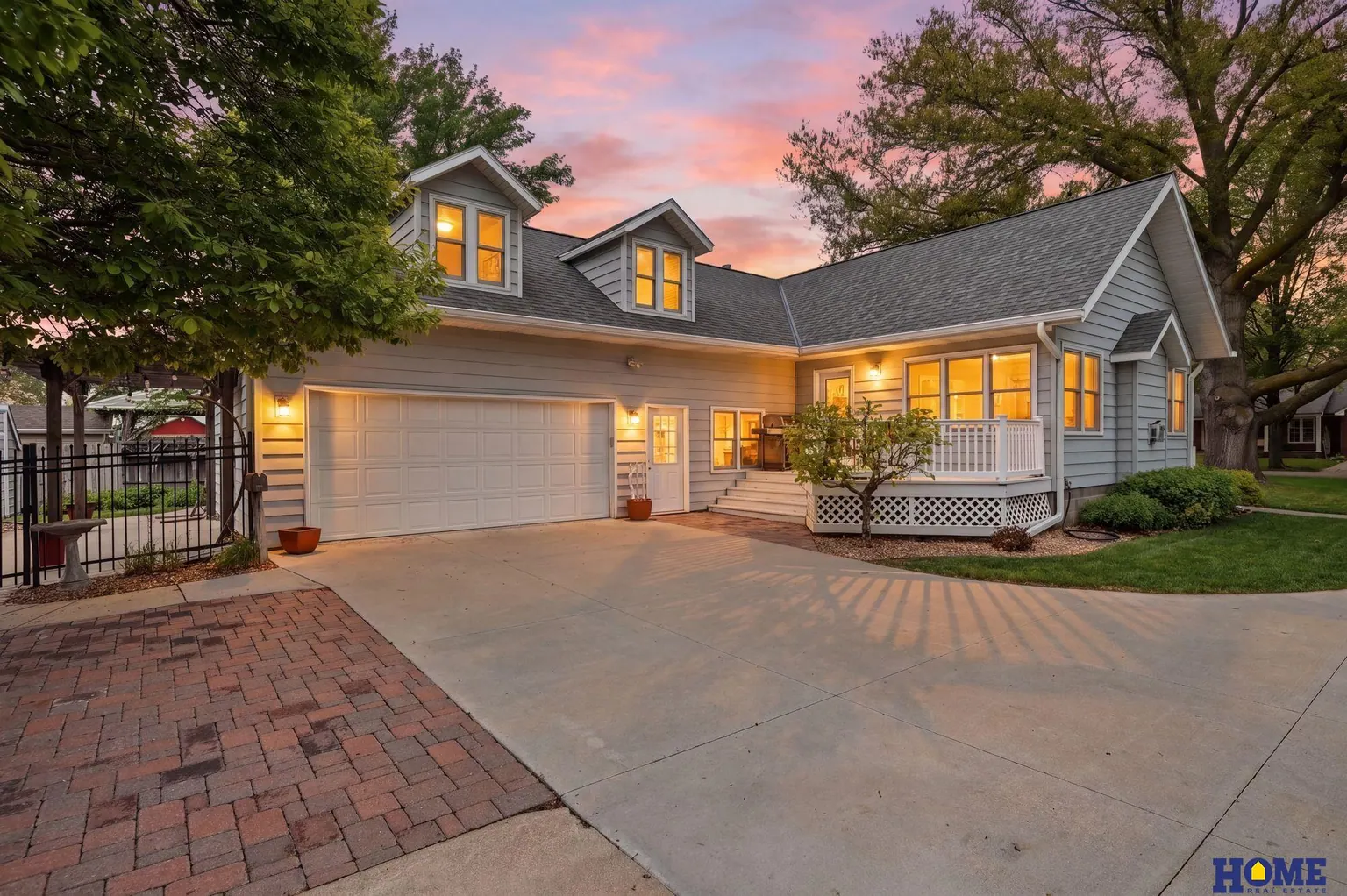 207 W 4th Street: 207 W 4th Street at dusk, gray siding and lit dormers above the attached garage
