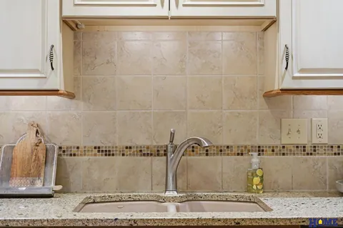 207 W 4th Street: kitchen double sink and tile backsplash with a mosaic band