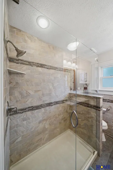 207 W 4th Street: walk-in shower with tile and an accent band