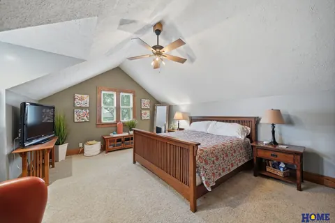 207 W 4th Street: primary bedroom with a vaulted ceiling and ceiling fan