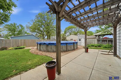 207 W 4th Street: pergola over a concrete patio, with the above-ground pool beyond